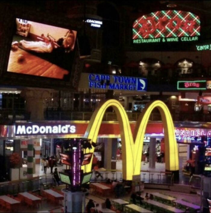 McDonald's golden arches inside a brightly lit mall with various neon signs, illustrating changes through the years online.
