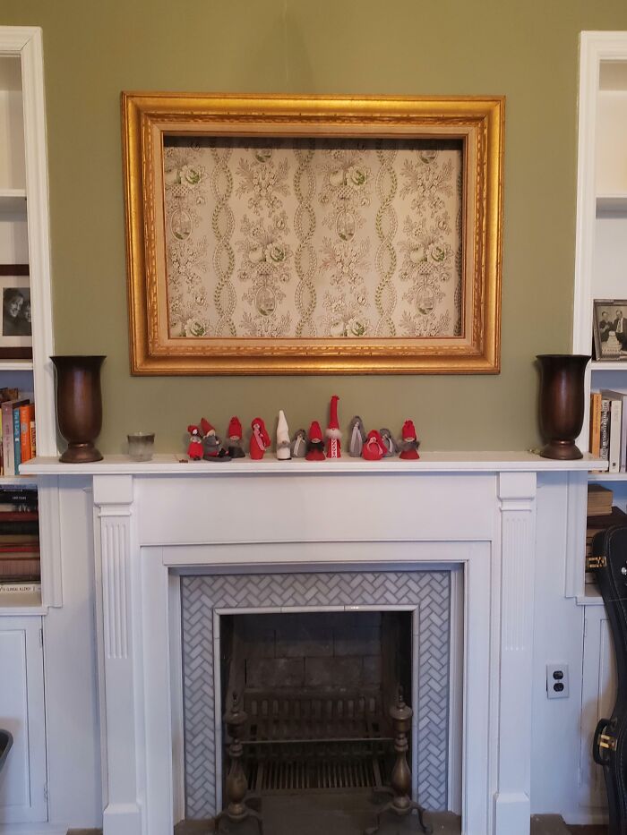 Vintage fireplace mantel with small figurines and an empty ornate gold frame showcasing how things used to look.