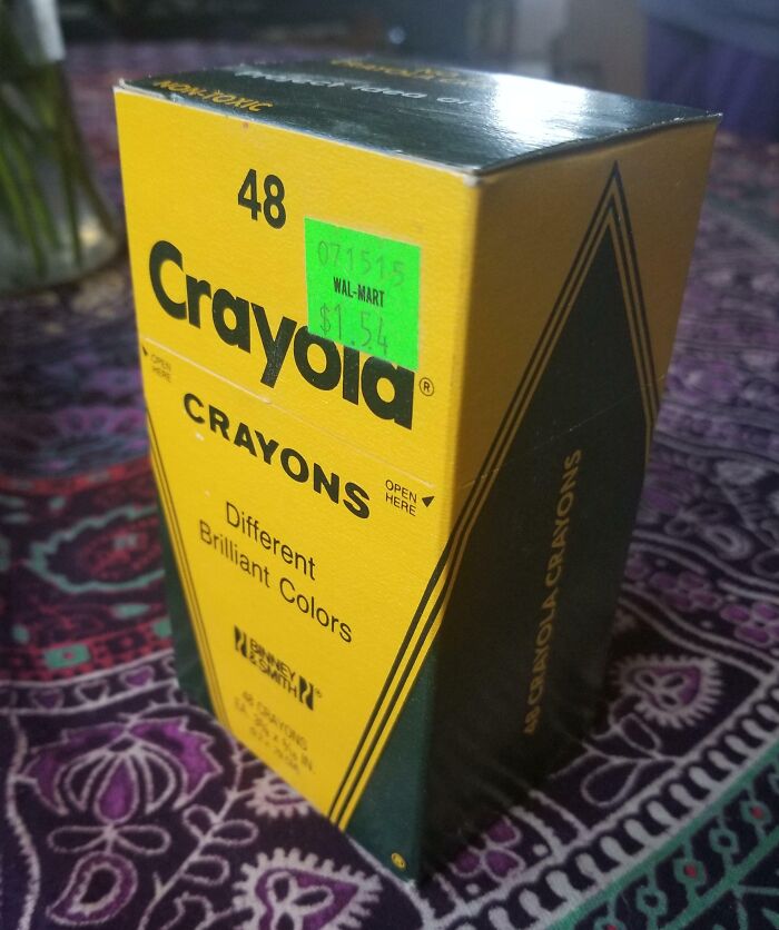 Vintage Crayola crayons box with 48 colors seen on a patterned surface, portraying how things used to look.