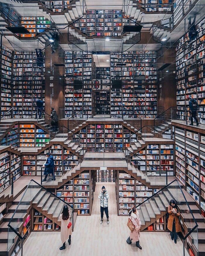Stunning and impressive bookstore interior with mirrored ceilings, multiple staircases, and walls filled with books in various colors.