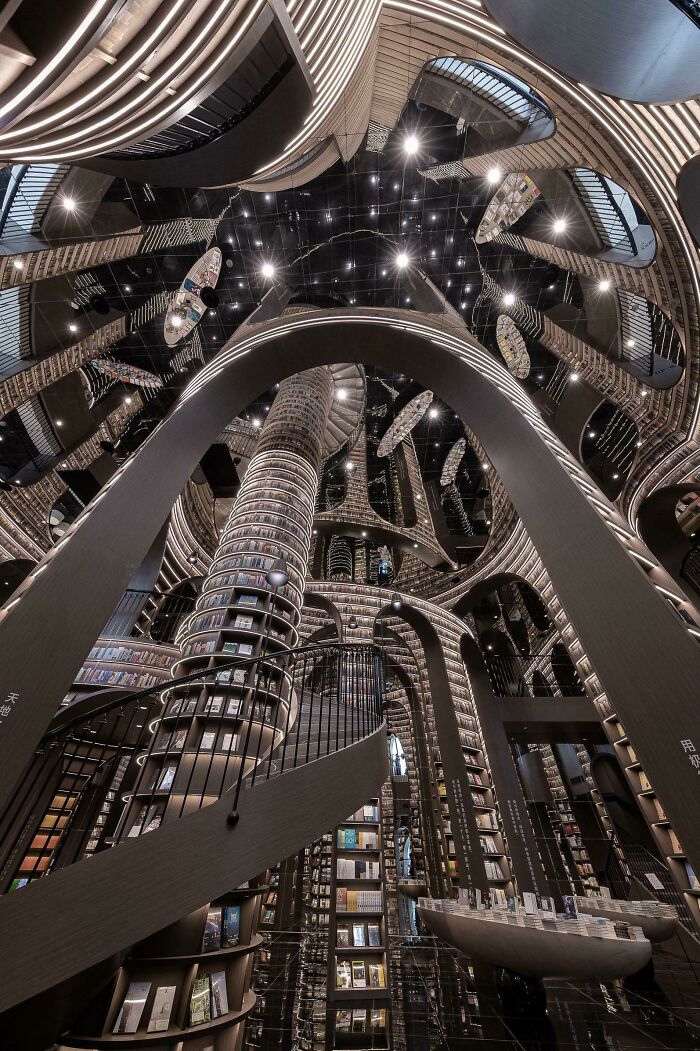 Futuristic and stunning bookstore interior with towering shelves, curved staircases, and reflective ceilings in an impressive library design
