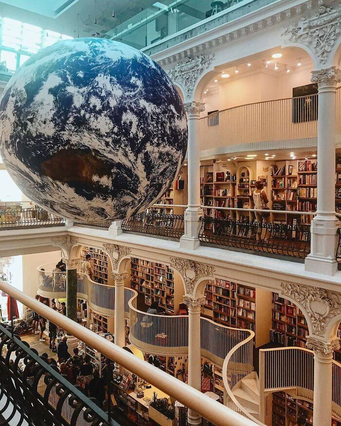 Stunning bookstore interior with large Earth globe installation, intricate balconies, and impressive shelves filled with books.