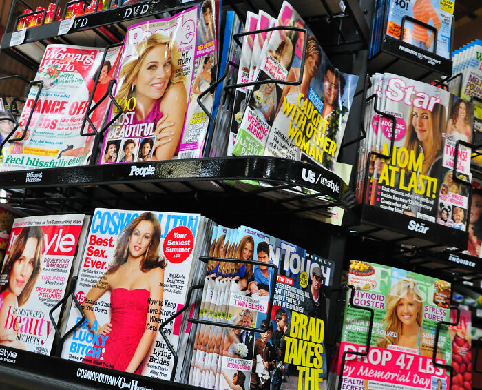 Magazine rack displaying diverse covers illustrating cultural differences and changing global perspectives on beauty and lifestyle.