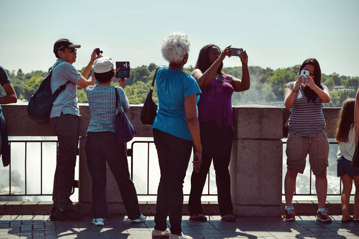 Tourists taking photos at a scenic outdoor location reflecting the decline in US tourism and its economic impact.