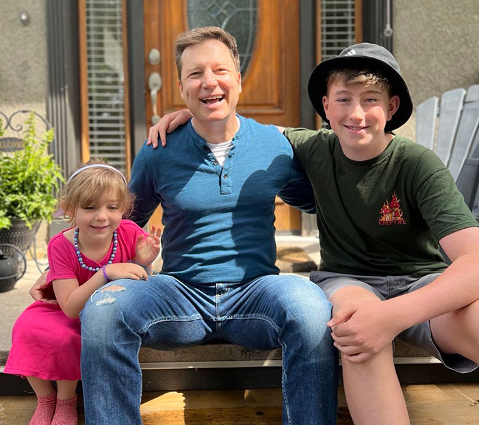 Hallmark actor sitting with two children on porch, smiling on a sunny day after Vancouver attack incident.