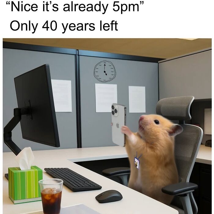 Hamster holding a smartphone at an office desk with a computer, relatable meme featuring sarcasm about work time.