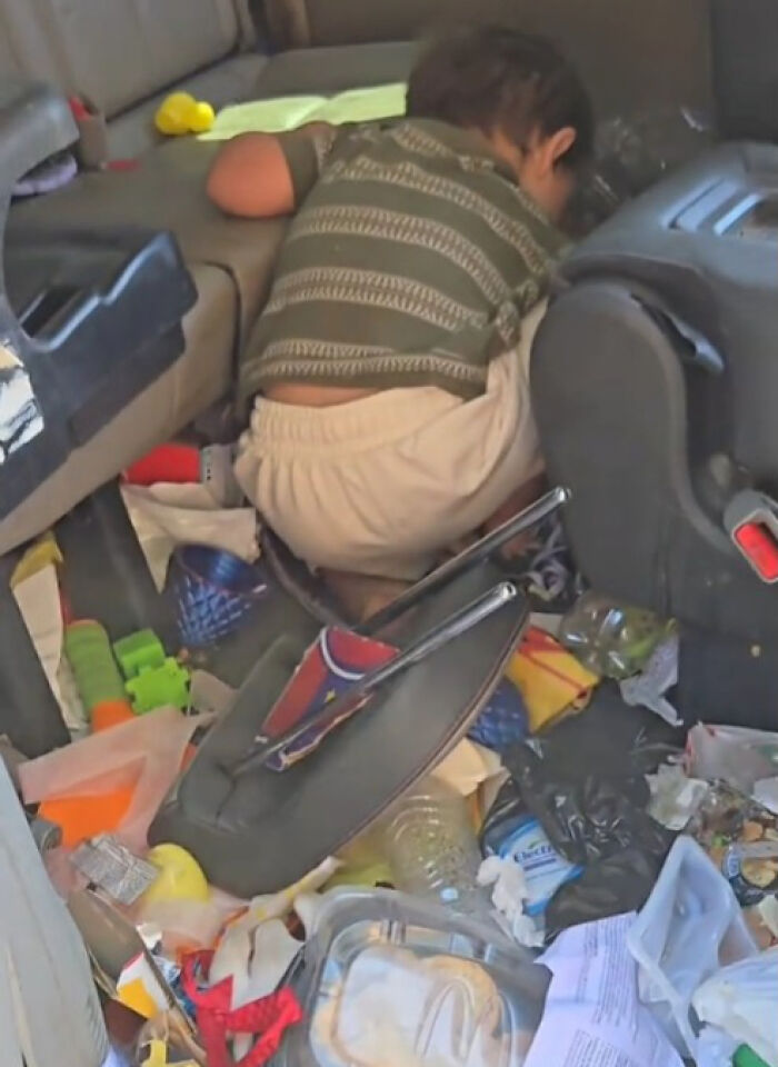 Child leaning into a cluttered car interior filled with trash and toys, highlighting filthy car cleaning challenges.