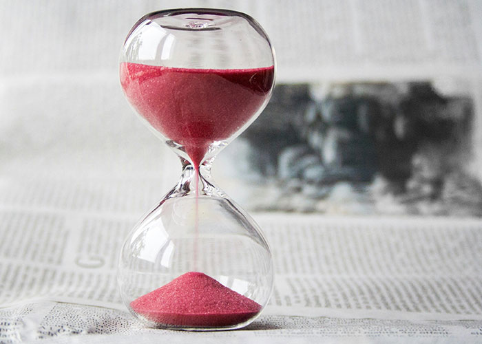 Close-up of an hourglass with red sand flowing, symbolizing time in entertaining facts shared on X thread.