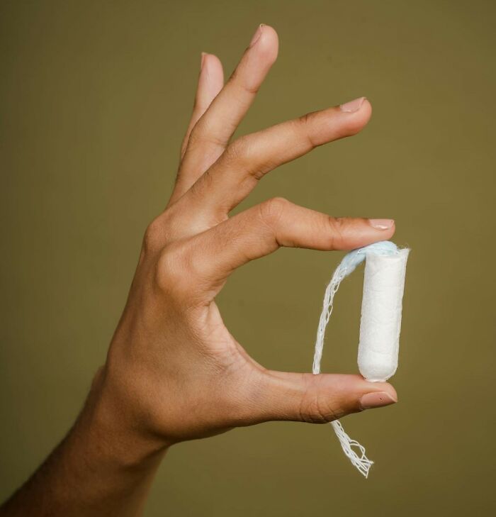 Hand holding a white tampon with string, representing excessively lazy things people have shared.