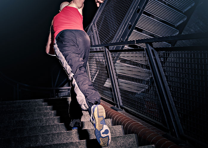 Person in sporty clothes walking up stairs at night, illustrating things everyone does but doesn’t talk about in daily life.