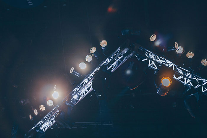Stage lighting rig with spotlights and beams shining in dark concert or event setting, gut feeling concept.