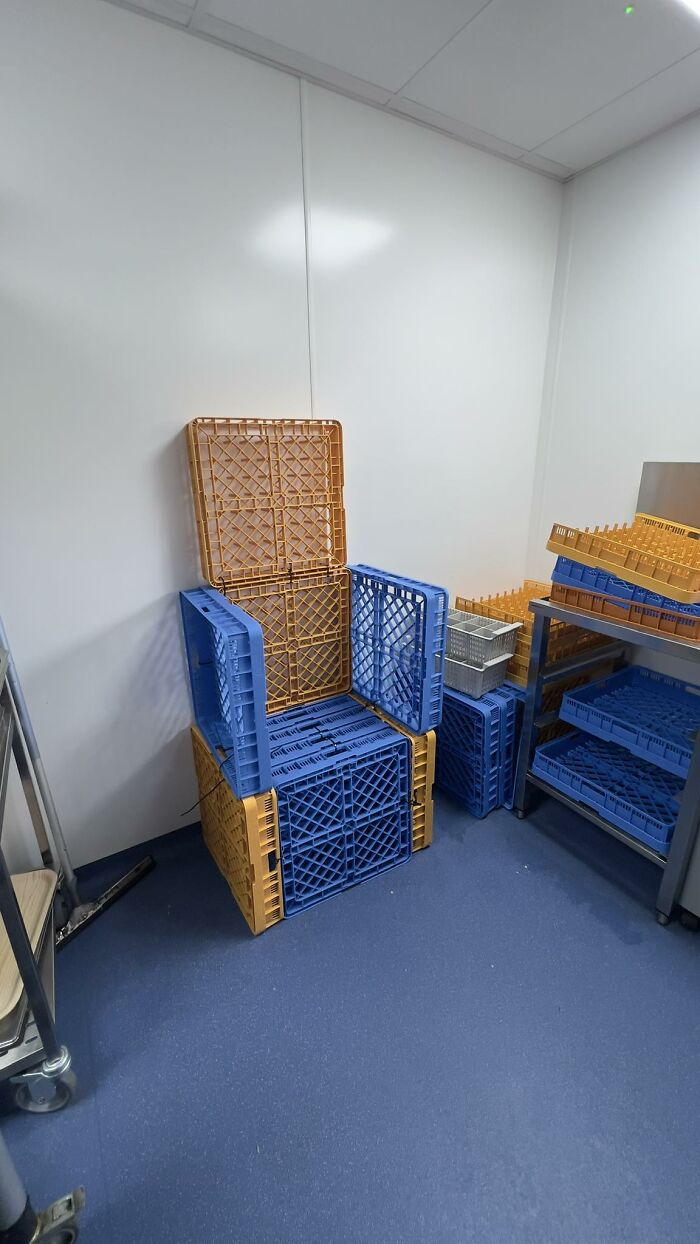 Stacked blue and orange plastic crates creatively arranged to form a chair in a hospitality workroom.