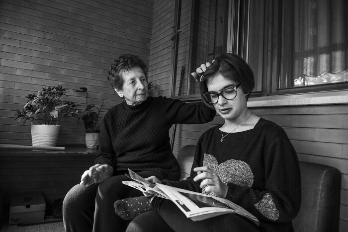 Elderly woman and young girl sharing a moment while reading, capturing the essence of humanity in a black and white photo.