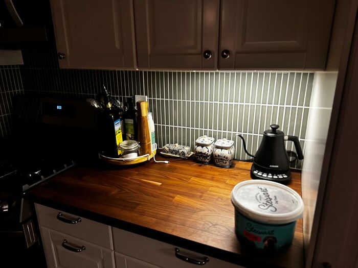 Wooden kitchen countertop with electric kettle, spice jars, and cooking utensils, highlighting popular affordable Amazon finds.