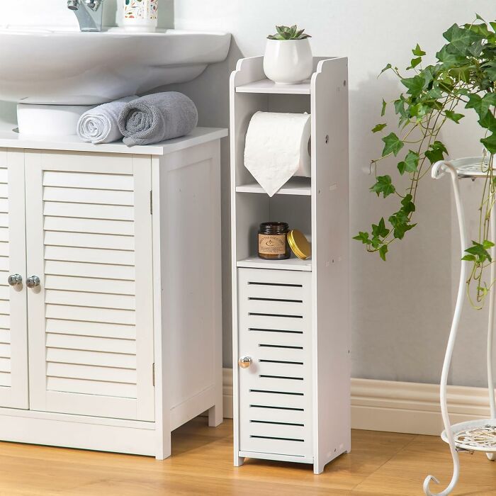 White bathroom storage cabinet with toilet paper holder and small plant, a popular Amazon find on many wishlists.