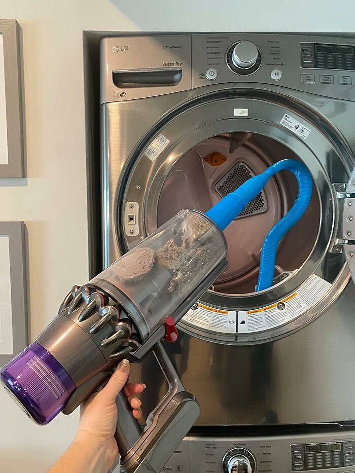 Hand holding a cordless vacuum cleaning lint trap inside a front-load dryer, showcasing bestselling home cleaning tools.