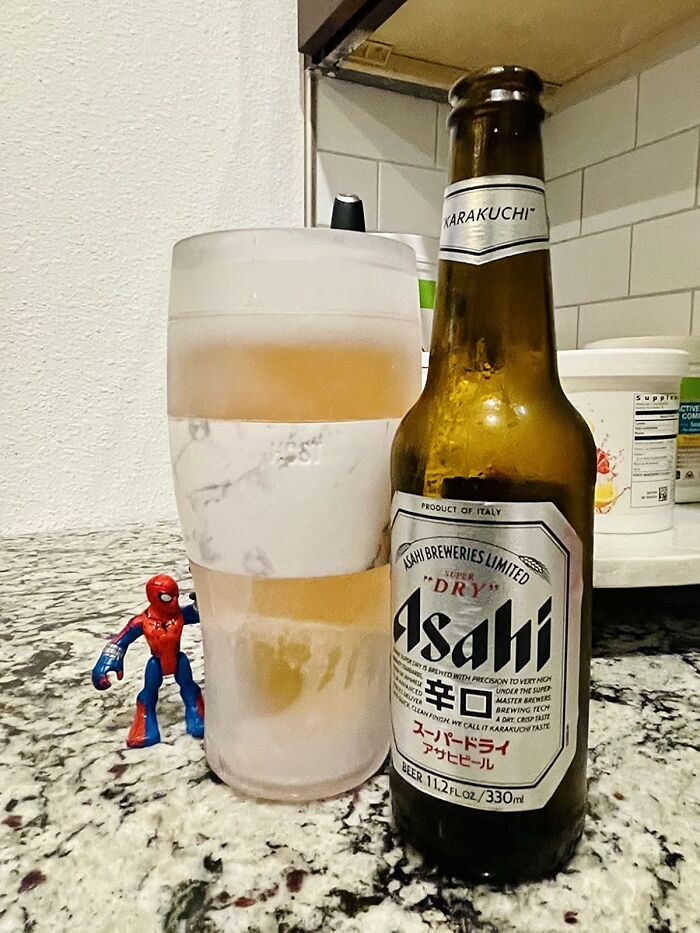 Frosted beer glass and Asahi bottle on a countertop with a small Spider-Man figure, perfect Father's Day finds.