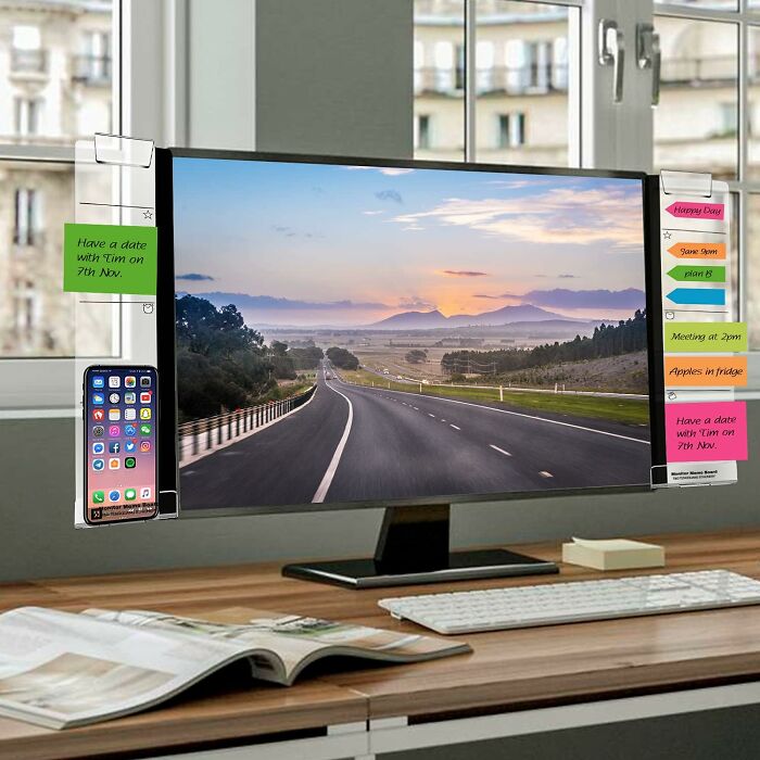 Desktop monitor with clear sticky note holders and phone organizer, showcasing innovative office supplies for an organized desk setup.