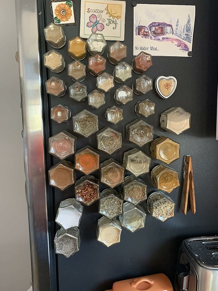 Magnetic spice jars organized on a refrigerator showcasing smart kitchen gadgets for efficient cooking space.