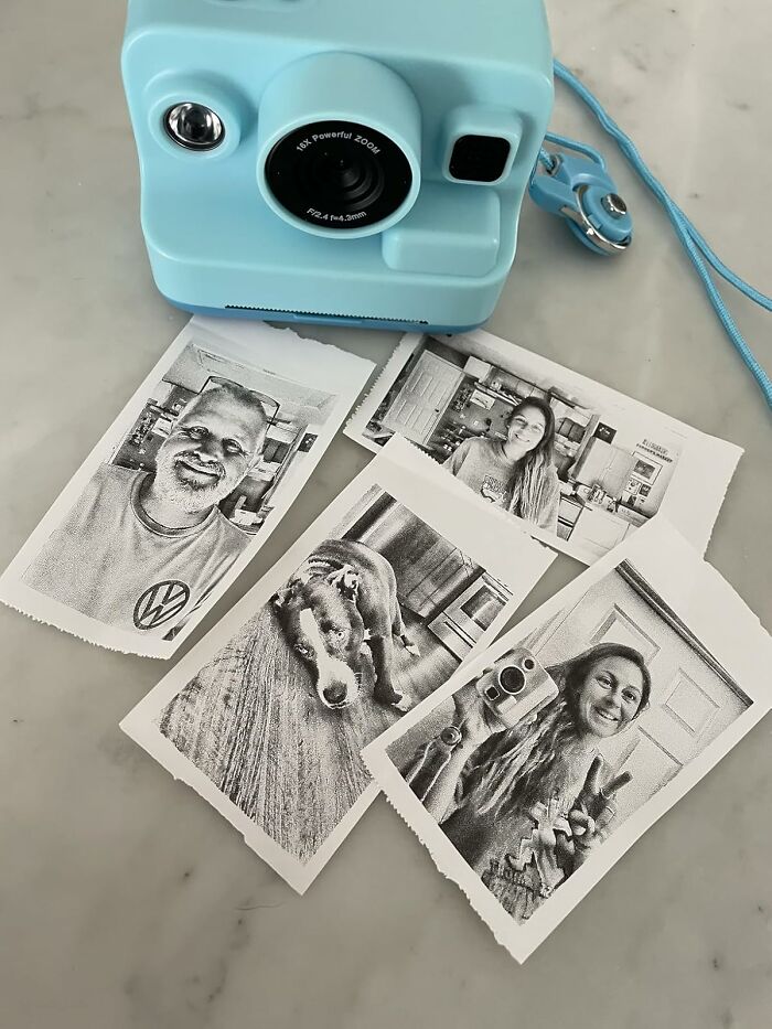 Compact blue instant camera with black and white printed photos of people and a dog, popular Amazon movers and shakers.