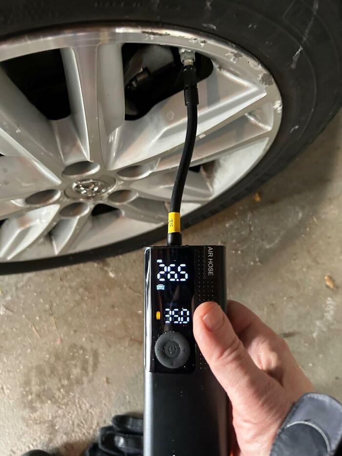 Hand holding a digital tire inflator pumping air into a car tire, a popular Amazon find on wishlists right now.