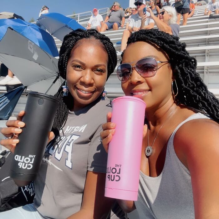 Two women smiling and holding tumblers while enjoying a sunny day exploring Amazon hidden gems outdoors.
