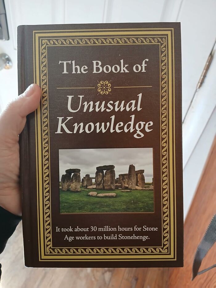 Hand holding The Book of Unusual Knowledge featuring Stonehenge image, a popular bestseller pandas are buying now.