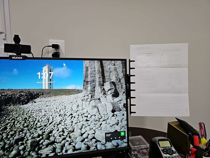 Computer monitor with webcam and document holder attached, showcasing innovative office supplies for an organized desk setup
