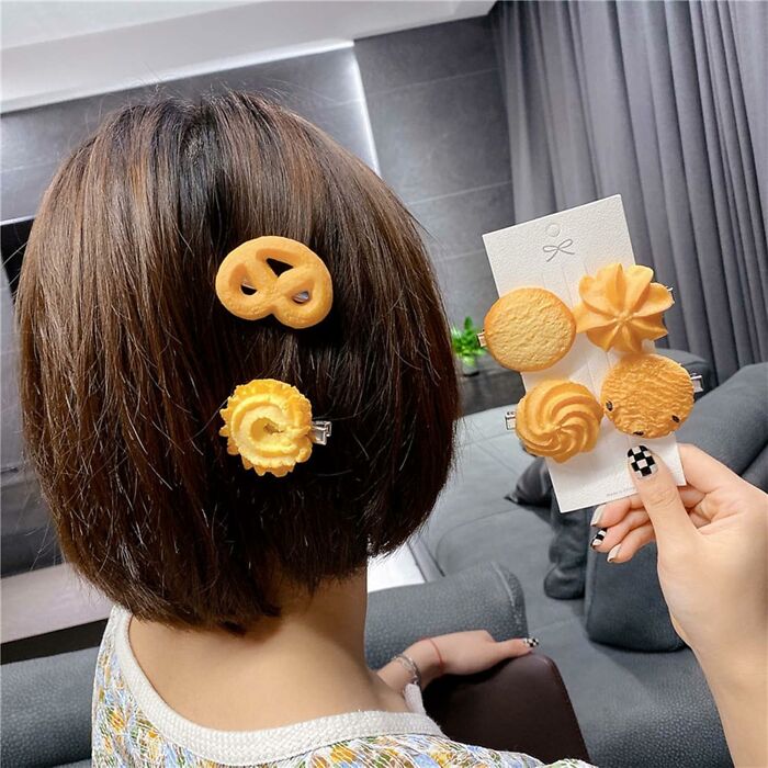 Hair clips shaped like various cookies worn by a person, showcasing weirdly wonderful finds in unique accessories.