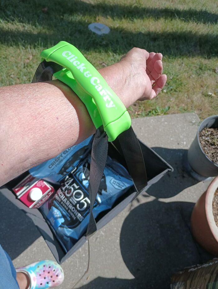 Green Click & Carry handle on wrist carrying groceries, showcasing popular Shark Tank pitches turned massive hits.
