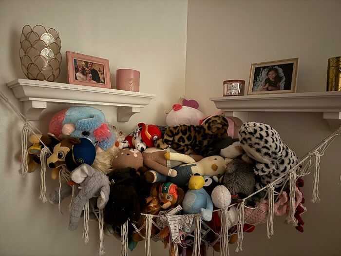 A cozy corner with affordable home finds featuring a hanging hammock full of plush toys and decorative shelves.