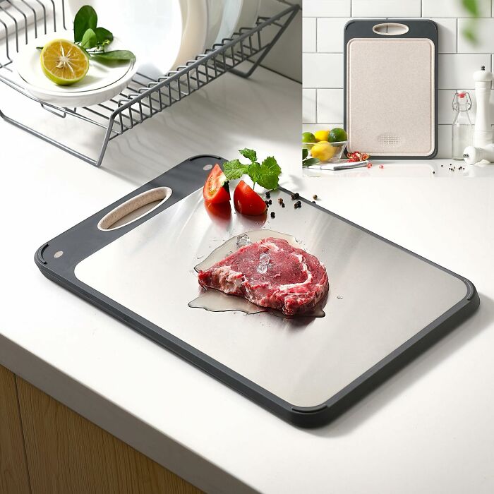 Chopping board with raw steak and tomato slices on a kitchen counter, showcasing popular TikTok kitchen finds.