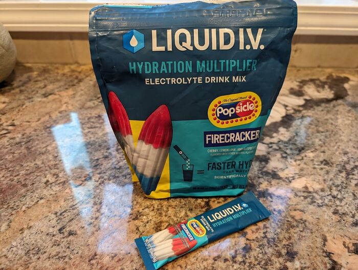 Liquid I.V. hydration multiplier electrolyte drink mix with Popsicle Firecracker flavor on a kitchen counter, summer essentials.