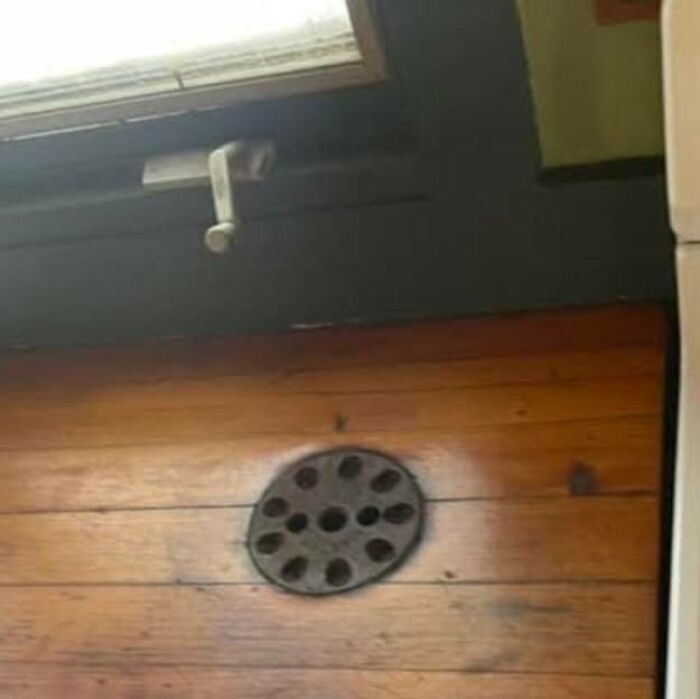 Old wooden floor with a mysterious circular vent, a strange thing found in homes with hidden or haunted pasts.