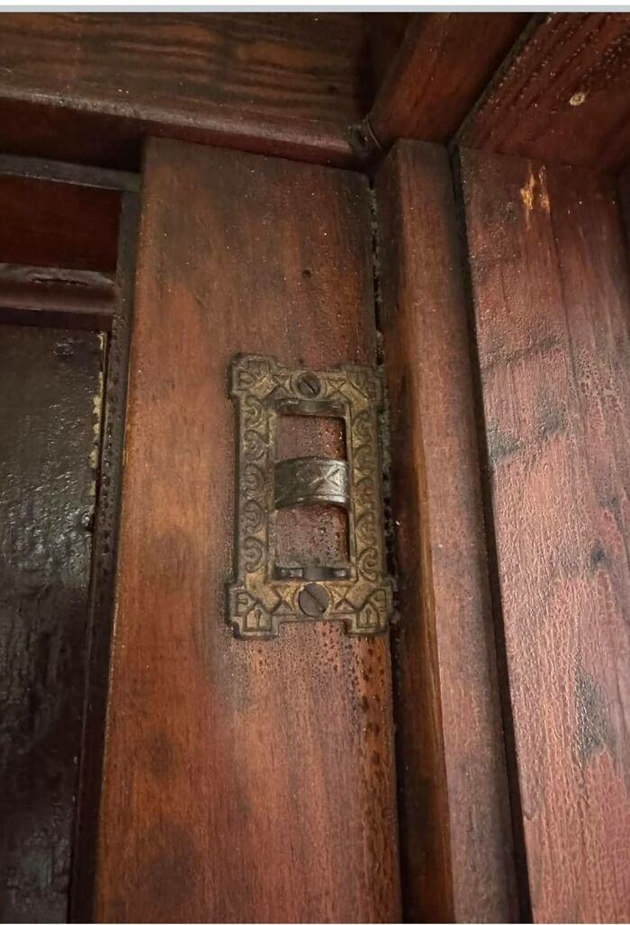 Antique wooden door with an ornate metal latch, one of the strange things found in homes with hidden pasts.