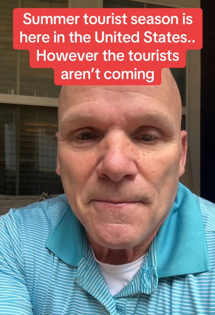 Man in a blue striped shirt discussing US tourism decline with text about tourists not coming this summer season.
