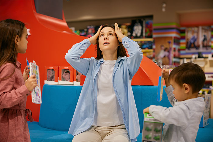 Stressed woman with two kids during a kid outing, highlighting challenges of refusing kid outings with brother&rsquo;s kids.