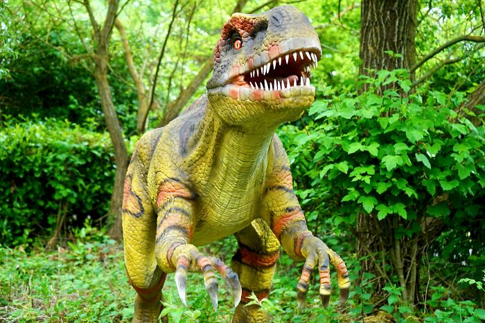Lifelike dinosaur model in green forest setting representing nostalgia for Gen X and their best of both worlds experience.