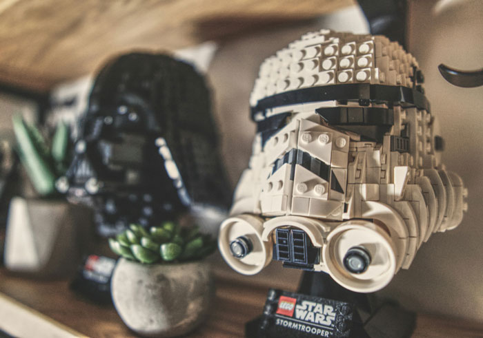 LEGO Star Wars Stormtrooper and Darth Vader helmets displayed on a wooden shelf with plants, secrets after marriage concept.