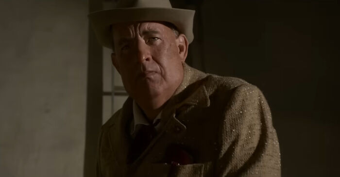Man in vintage suit and hat portraying a miscast actor in a dramatic movie scene with moody lighting.