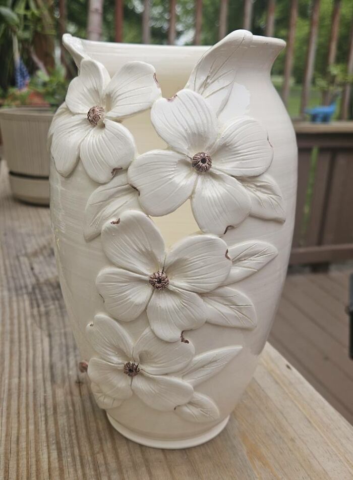 Ceramic vase with raised flower details on wooden table, a thrifted find that is both weird and wonderful.