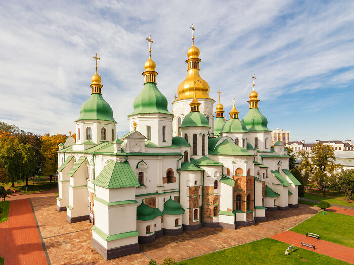 UNESCO treasure showcasing historic architecture with green and gold domes under a bright sky in a scenic park setting