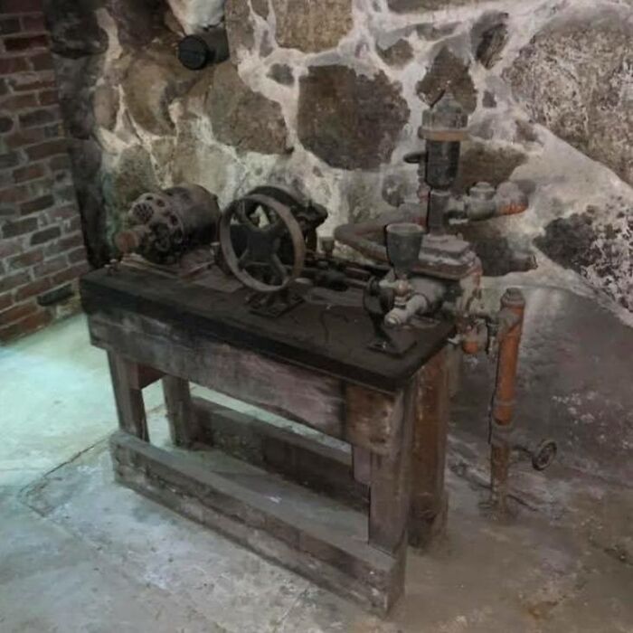 Old, rusty mechanical device on a wooden table in a basement, one of the strange things found in homes with hidden pasts.