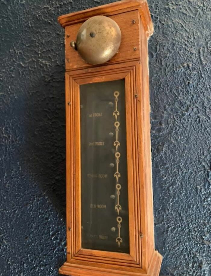 Vintage wooden elevator floor indicator with metal bell found in a home with a hidden or haunted past.