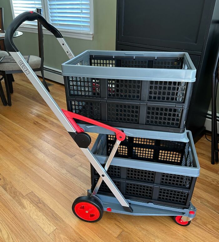 Collapsible utility cart with red wheels and stacked black plastic baskets on a wooden floor indoors, a weirdly wonderful find.