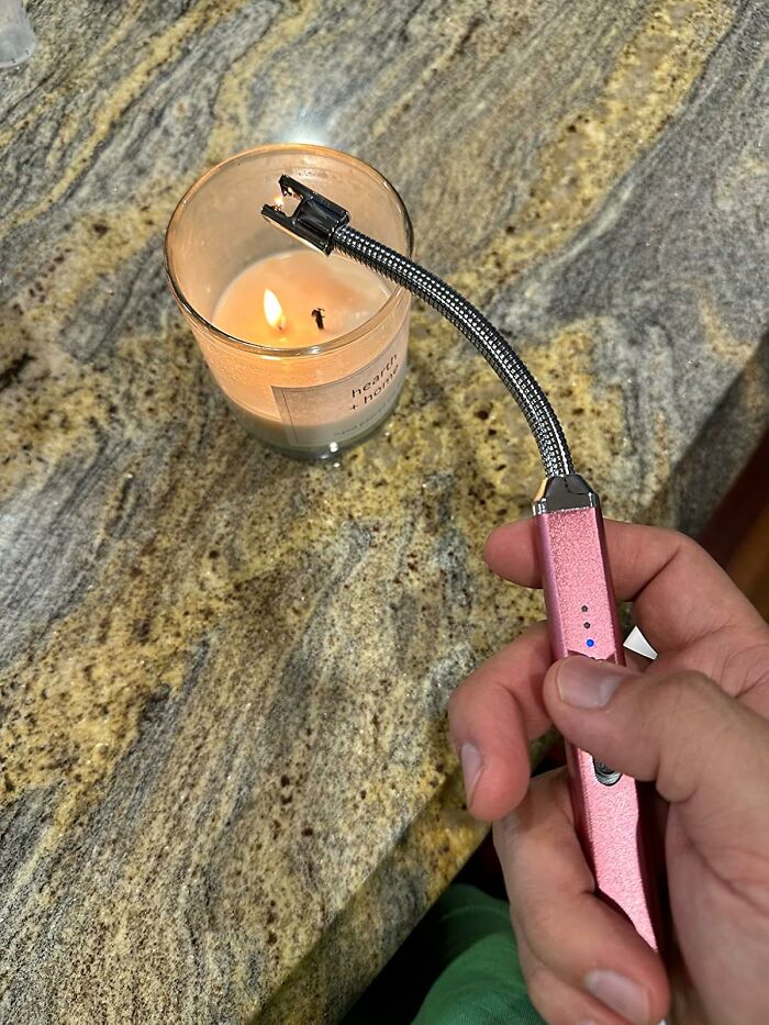 Hand holding a flexible tech gadget lighter igniting a candle, showcasing innovative Amazon tech finds.