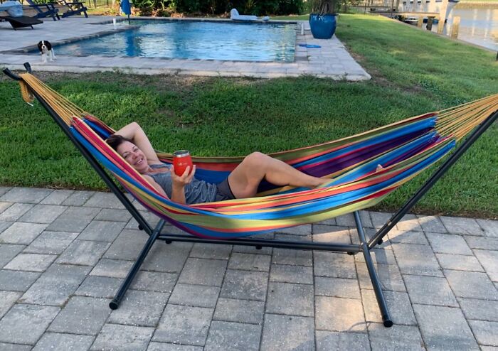 Woman relaxing in a colorful hammock by a pool, showcasing outdoor upgrades to make your backyard a summer hotspot.