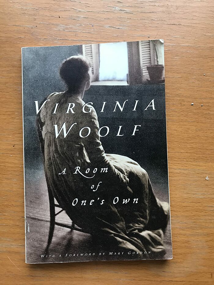 Book cover of Virginia Woolf's A Room of One's Own placed on a wooden surface, highlighting excellent books recommended by readers.