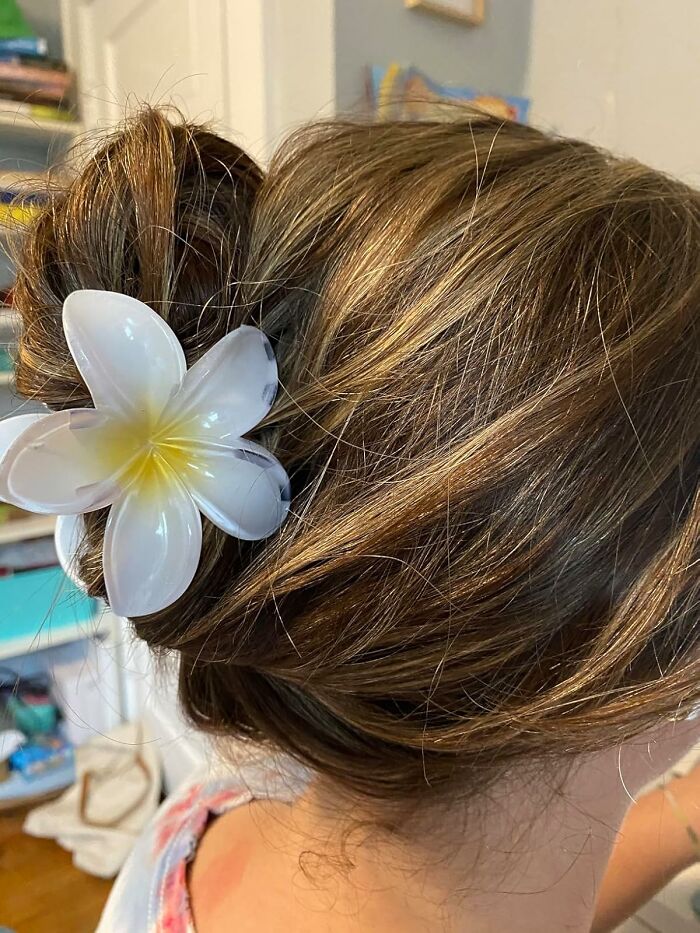 Woman with brown hair styled in a bun secured with a white flower hair accessory, a viral summer essential item.