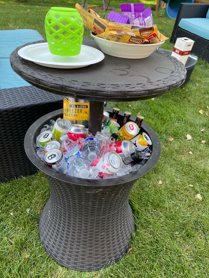 Outdoor upgrades for backyard featuring wicker side table with built-in cooler filled with drinks and snacks on top.